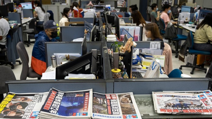 Na archívnej snímke z 26. apríla 2021 reportéri pracujú v redakcii hongkonského denníka Apple Daily.