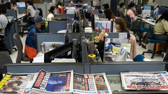 Na archívnej snímke z 26. apríla 2021 reportéri pracujú v redakcii hongkonského denníka Apple Daily.