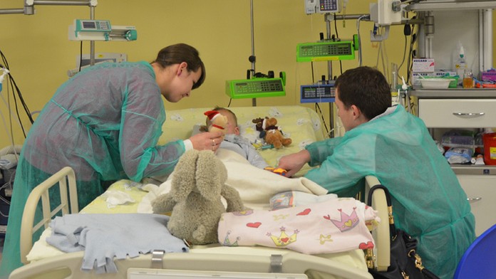 Mama Paulina a otec Mateusz sa skláňajú nad svojím dvojročným synom Adamom v nemocničnej izbe v detskej nemocnici v Krakove.