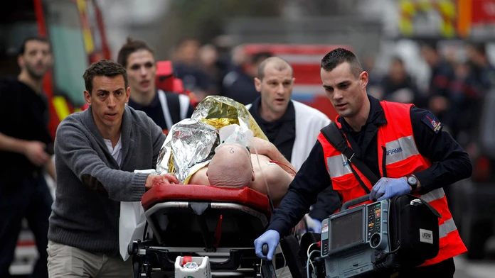Zdravotníci evakuujú zranenú osobu z redakcie francúzskeho satirického týždenníka Charlie Hebdo 7. januára 