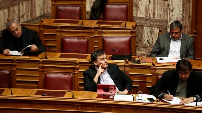 Grécky minister financií Euclid Tsakalotos (v strede) počas zasadnutia parlamentu pred hlasovaním o rozpočte v Aténach.