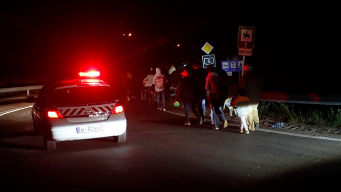 Maďarskí policajti monitorujú migrantov, ktorí sa rozhodli opustiť záchytný tábor pre utečencov.