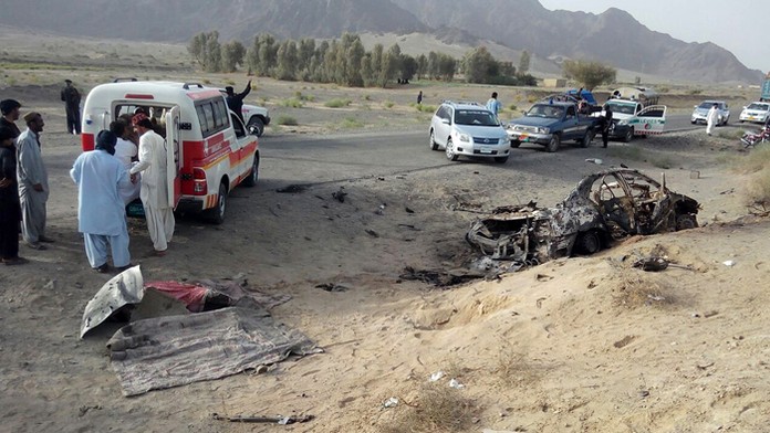Dobrovoľníci stoja pri vraku auta, v ktorom údajne zahynul vodca Talibanu mulla Muhammad Achtar Mansúr.