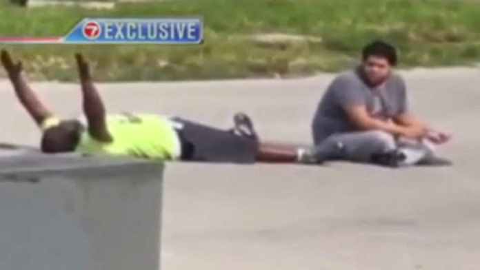 Muž ležal na zemi s rukami nad hlavou. 