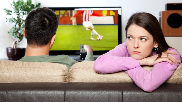 Muž pozerá futbal, žena sa nudí.