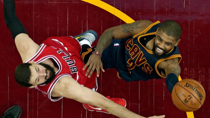 Na snímke vpravo hráč Cavaliers Kyrie Irving strieľa na kôš cez hráča Bulls Nikolu Mirotiča.