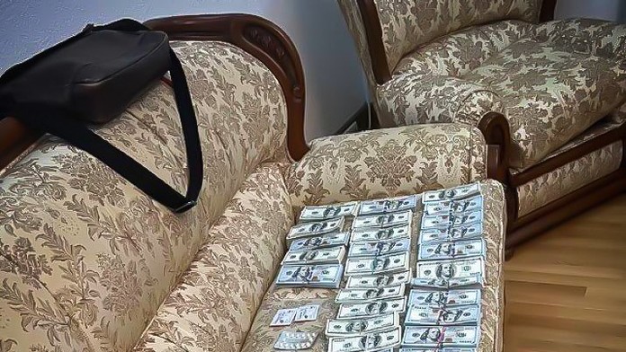 Bankovky rozložené na pohovke.