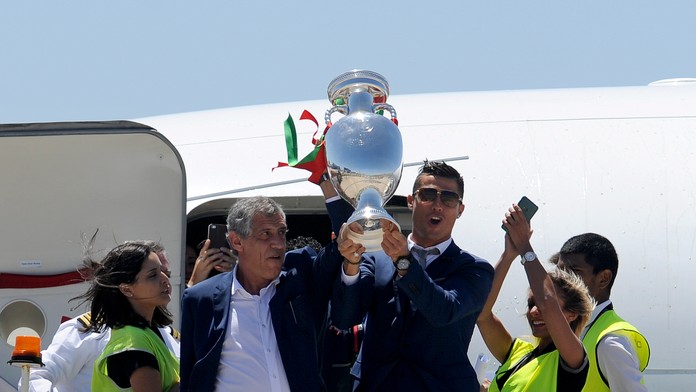 Cristiano Ronaldo a tréner Fernando Santos zdvíhajú pohárovú trofej majstrov Európy po prílete na letisko v Lisabone.