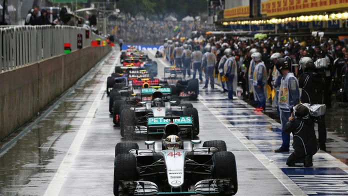 Lewis Hamilton stojí na čele monopostov v boxovej uličke počas prerušenia preteku pre nehodou Kimiho Räikkönnena.