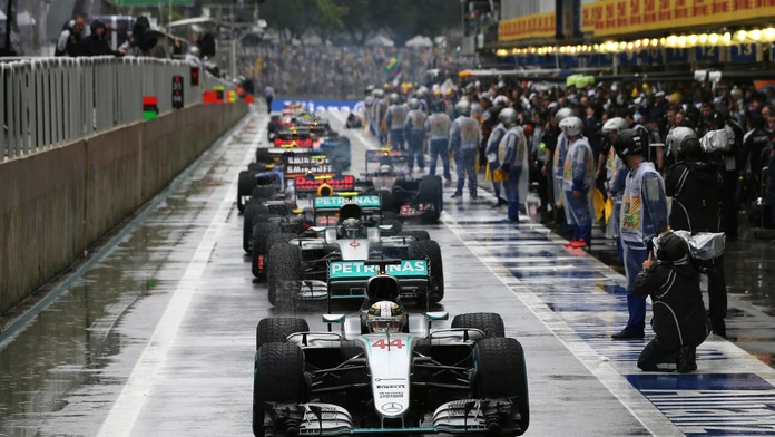 Lewis Hamilton stojí na čele monopostov v boxovej uličke počas prerušenia preteku pre nehodou Kimiho Räikkönnena.
