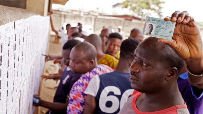 Voliči čítajú volebné zoznamy pred volebnou miestnosťou v nigerijskom meste Lagos.