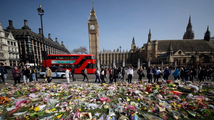 Kvety za obete teroristického útoku z 22. marca 2016 sú položené pred Westminsterským palácom 27. marca 2017 v Londýne..jpg