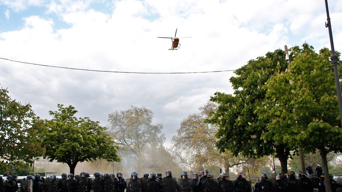 Vrtuľník letí nad príslušníkmi poriadkovej polície v Paríži.