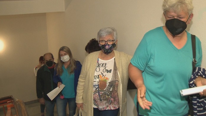 Ľudia čakajú na očkovanie v rade na schodoch.