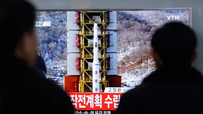 Ľudia sledujú televízne spravodajstvo o vypustení rakety dlhého doletu.