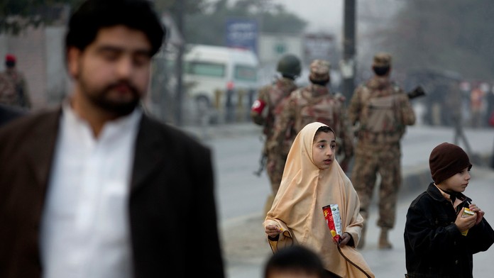 Rodinný príslušník odvádza deti mimo školy, na ktorú v pakistanskom Pešaváre zaútočil Taliban. 16. decembra 