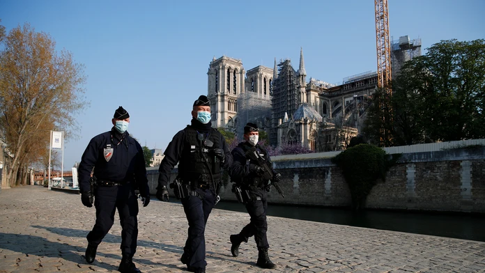 Policajti hliadkujú pozdĺž rieky Seiny, v pozadí katedrála Notre-Dame počas druhého výročia ničivého požiaru.
