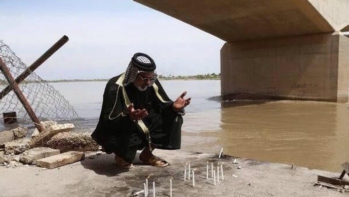 Muž sa modlí pri masovom hrobe v irackom meste Tikrit