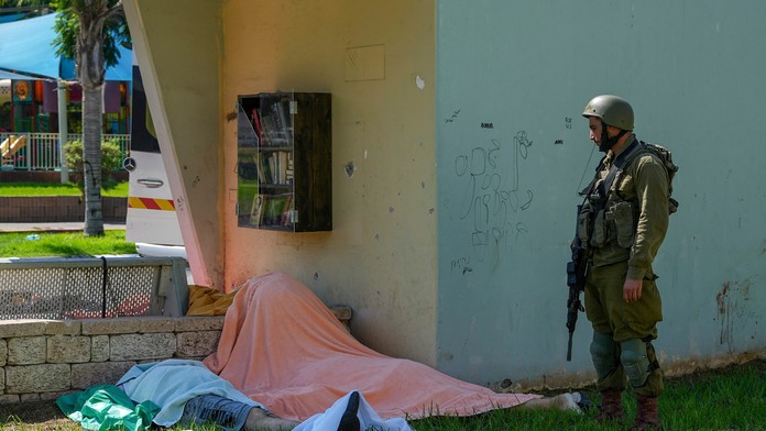 Izraelský vojak stojí pri telách Izraelčanov zabitých palestínskymi ozbrojenými militantmi.