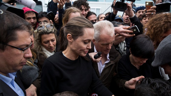 Utečenecký chlapec dáva na ruku náramok osobitnej vyslankyni UNHCR Angeline Jolieovej v gréckom prístavnom meste Piraeus.