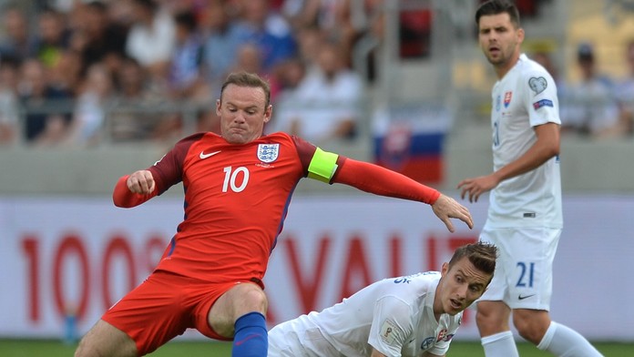 V strede o loptu bojujúci Ján Greguš proti kapitánovi Anglicka Wayneovi Rooneymu a spoluhráčovi Michalovi Ďurišovi.