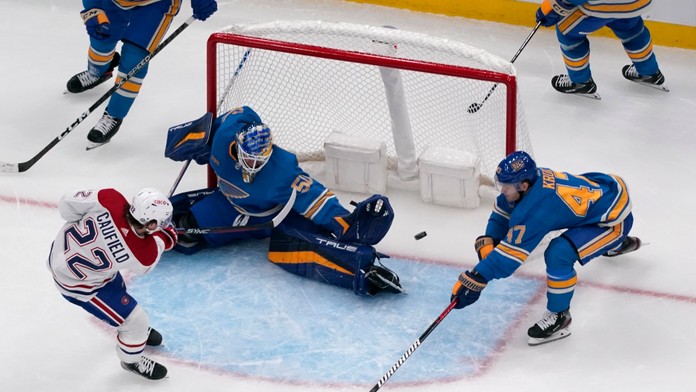 Hokejista Montrealu Canadiens Cole Caufield (vľavo) prekonáva brankára St. Louis Blues Jordana Binningtona