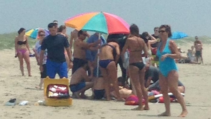 Ľudia sa zhromažďujú okolo zraneného 68-ročného muža, ktorého napadol žralok vo vode siahajúcej po pás na pobreží Ocracoke Islan