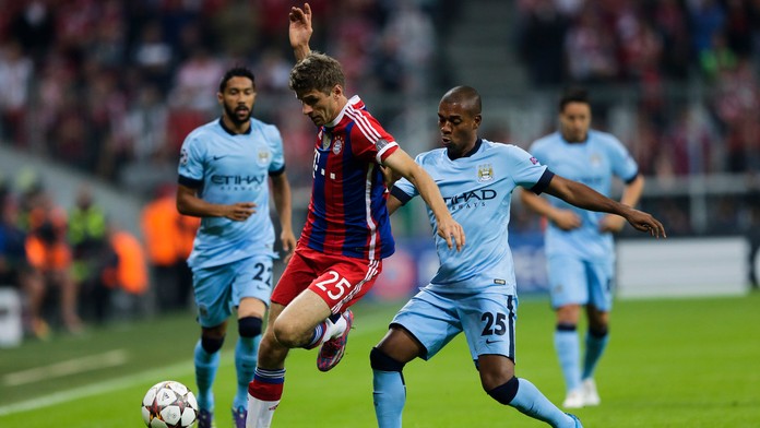Hráč Bayernu Thomas Müller (vľavo) a hráč Manchestru Fernandinho (vpravo) bojujú o loptu v zápase Ligy majstrov skupiny E
