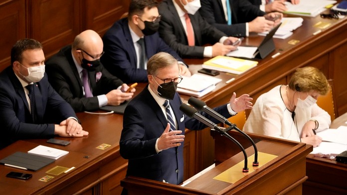 Český premiér Petr Fiala (ODS) stojí za rečníckym pultom počas zasadnutia parlamentu.