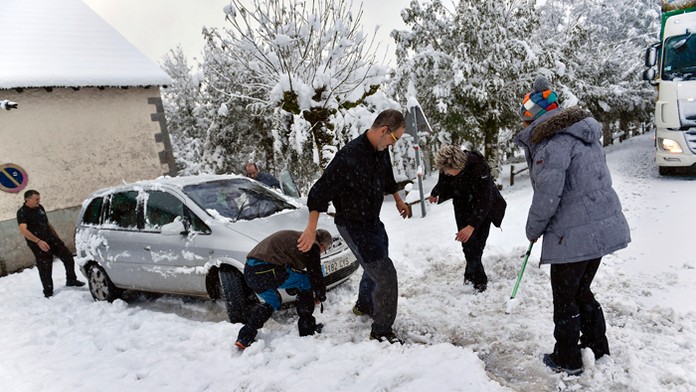 Ľudia pomáhajú odhrabať auto po silnom snežení v severošpanielskom Roncesvallese.