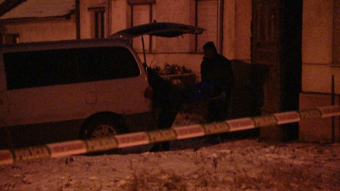Pohrebná služba vynáša mužove telo z domu.