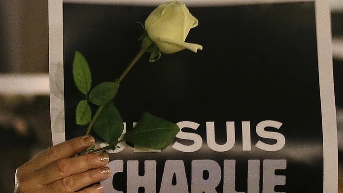 Žena drží plagát s nápisom "Ja som Charlie" a ružu pri spomienke na Charlie Hebdo