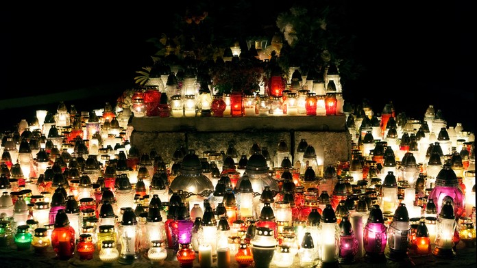 Na snímke je hrob, na ktorom horí množstvo sviečok. Je noc a je tma. 