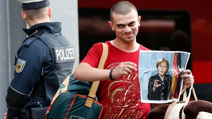 Utečenec zo Sýrie drží portrét nemeckej kancelárky  Angely Merkelovej počas príchodu na hlavnú železničnú stanicu v nemeckom Mní