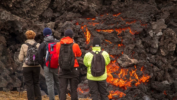 Turisti pri tečúcej láve islandskej sopky