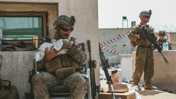 Americký vojak tíši na rukách afganské batoľa na letisku v Kábule.