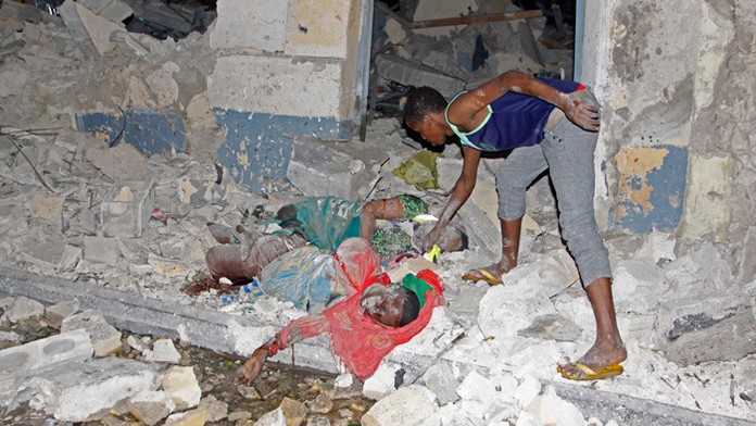 Somálčan stojí pri mŕtvych telách po samovražednom bombovom útoku na hotel v Mogadišu.