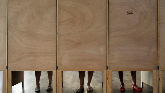 Ženy upravujú volebné lístky v kabínkach vo volebnej miestnost