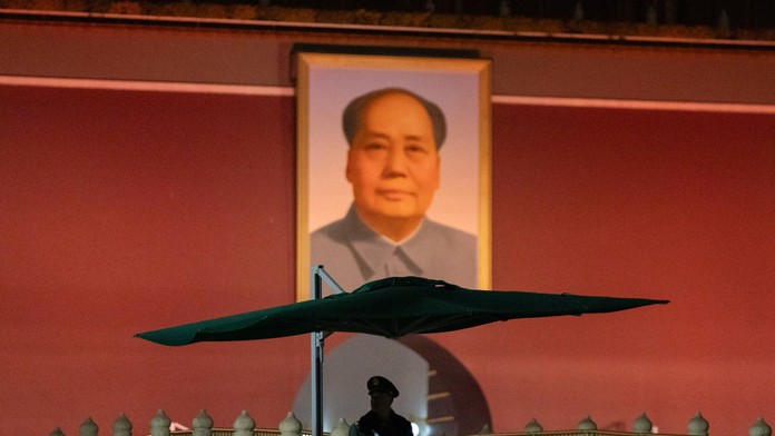 Čínsky policajt stojí na stráži pri portréte Mao Ce-tunga.