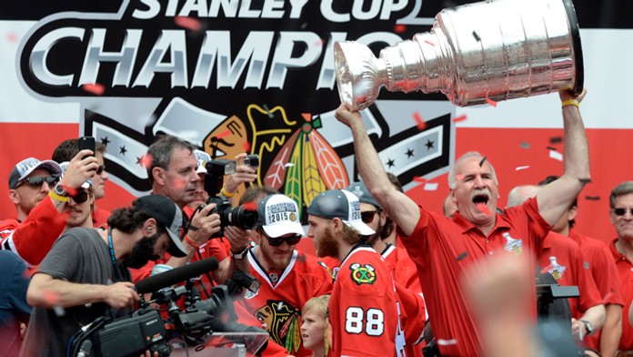 Tréner Chicaga Blackhawks Joel Quenneville dvíha nad hlavu Stanleyho pohár počas osláv titulu, Hossa si všetko fotí.