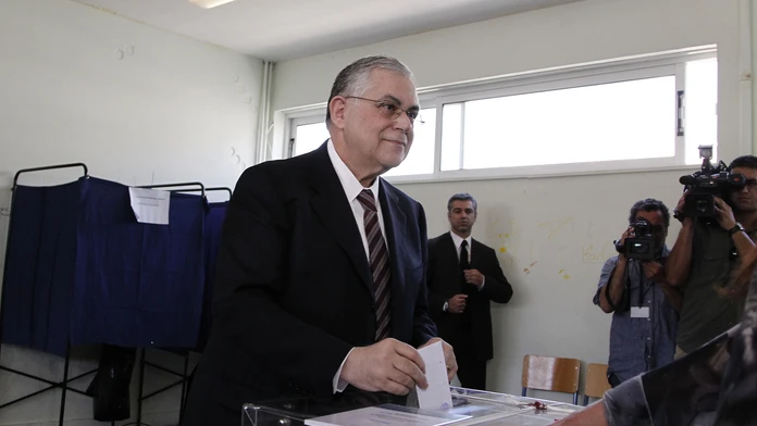 Grécky vtedy ešte premiér Lucas Papademos hlasuje počas parlamentných volieb 6. mája 2012 v Aténach. (archív)