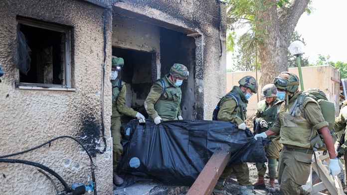Izraelskí vojaci vynášajú telá z domov v kibuci Kfar Aza
