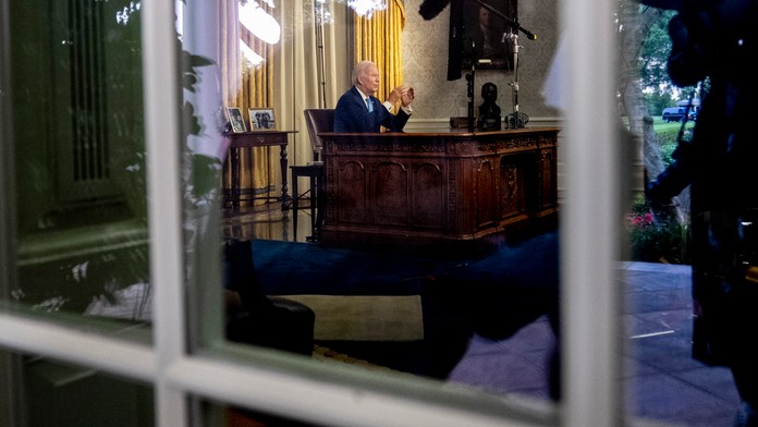 Joe Biden sedi za stolom vo svojej pracovnice v Bielom dome.