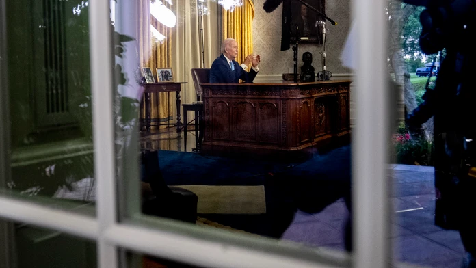 Joe Biden sedi za stolom vo svojej pracovnice v Bielom dome.