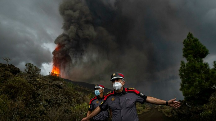 Policajt stráži miesto, kde uniká láva.