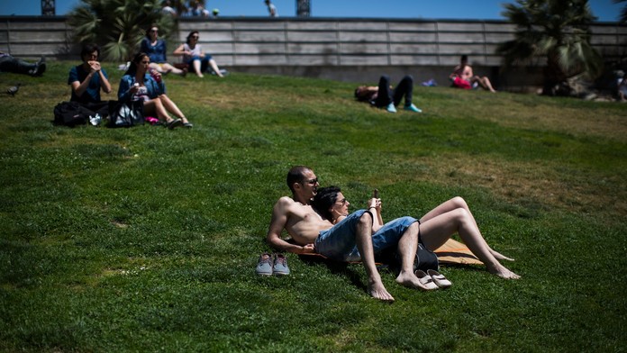 Ľudia sa opaľujú v parku v Barcelone.