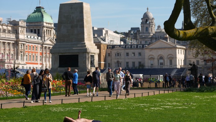 N snímke muž sa opaľuje počas slnečného dňa v parku St James's Park v Londýne.