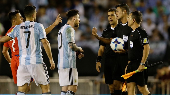 Lionel Messi (v strede) z Argentíny v debate s čiarovým arbitrom Sandrom Riccim v dueli kvalifikácie proti Čile.