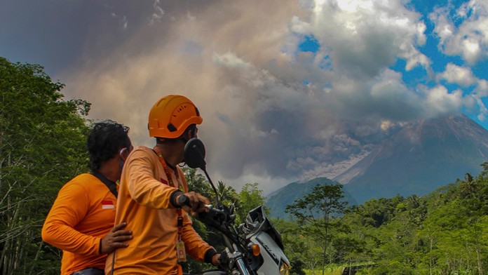 Muži sledujú erupciu sopky Merapi v indonézskom meste Sleman.
