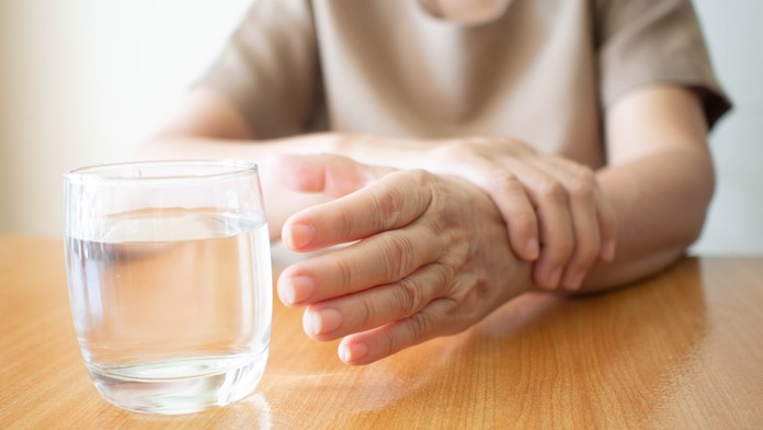 Žena sa snaží chytiť pohár vody.